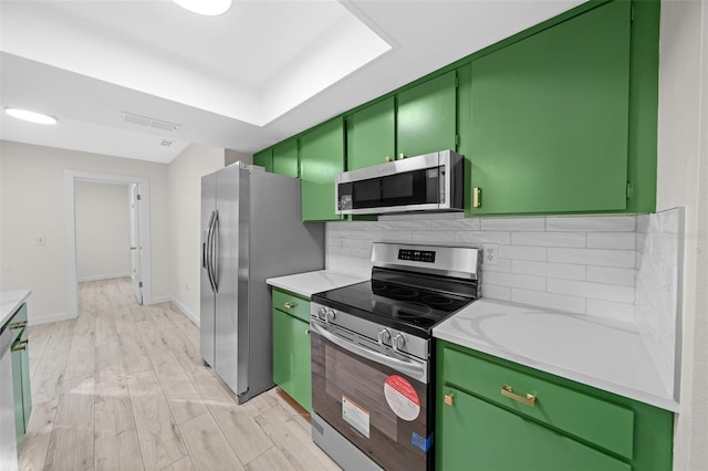 kitchen featuring stainless steel appliances, light hardwood / wood-style floors, green cabinets, and decorative backsplash