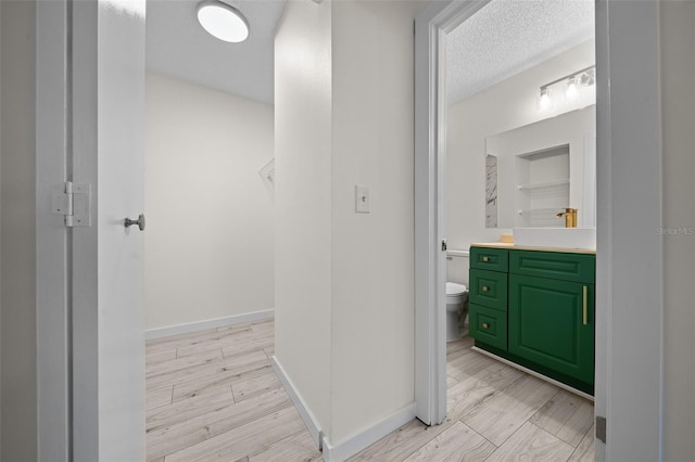 bathroom with hardwood / wood-style flooring, vanity, toilet, and a textured ceiling