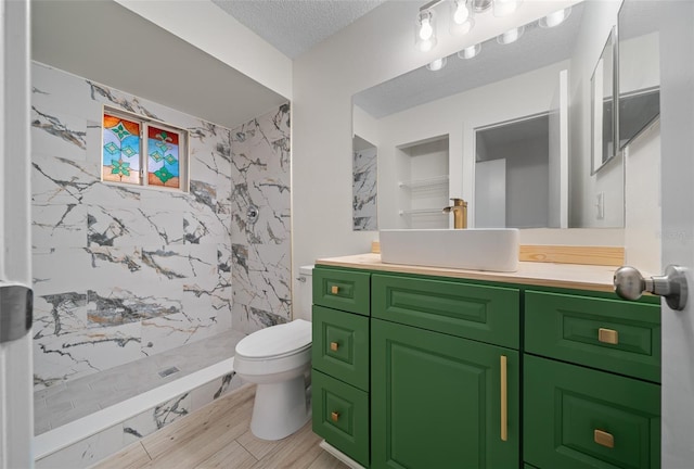 bathroom with vanity, a tile shower, a textured ceiling, and toilet