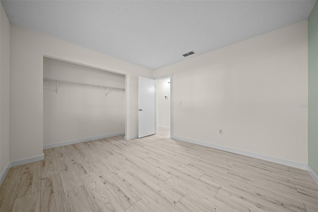 unfurnished bedroom with light hardwood / wood-style floors, a closet, and a textured ceiling