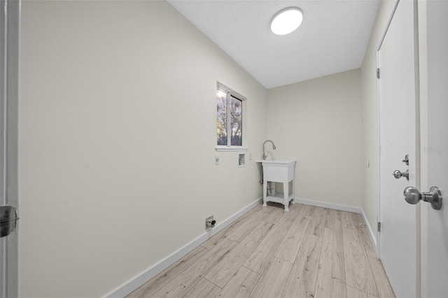 laundry room featuring washer hookup, light hardwood / wood-style floors, electric dryer hookup, and a textured ceiling