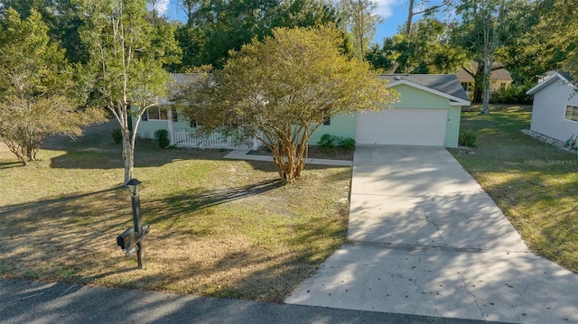 view of property hidden behind natural elements featuring a garage, a front lawn, and covered porch