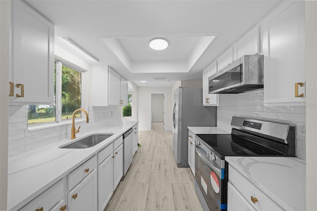7556 SW 112th Ln, Ocala, FL 34476 - kitchen featuring a raised ceiling, stainless steel appliances, white cabinets, and a sink
