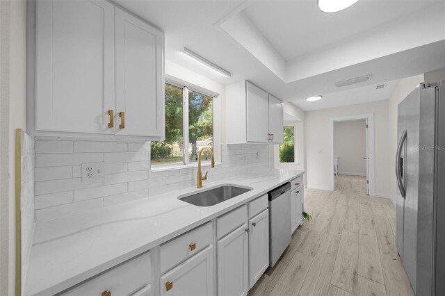 7556 SW 112th Ln, Ocala, FL 34476 - kitchen featuring a sink, white cabinets, light stone countertops, appliances with stainless steel finishes, and tasteful backsplash