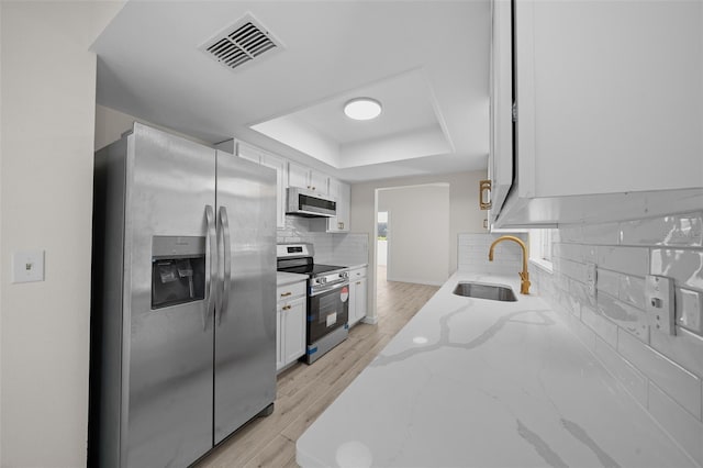 7556 SW 112th Ln, Ocala, FL 34476 - kitchen featuring a sink, a tray ceiling, stainless steel appliances, white cabinetry, and visible vents