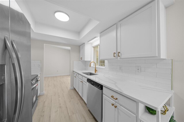7556 SW 112th Ln, Ocala, FL 34476 - kitchen featuring light wood finished floors, a sink, stainless steel appliances, white cabinets, and a raised ceiling
