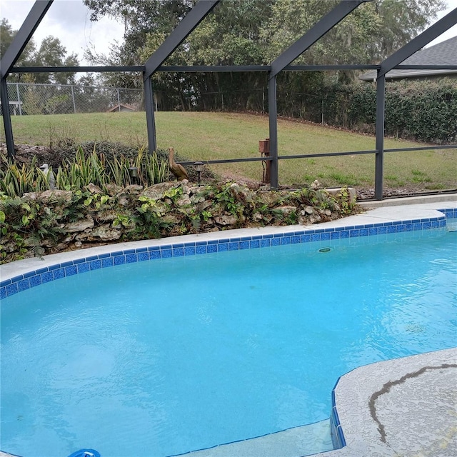 outdoor pool featuring glass enclosure and a yard