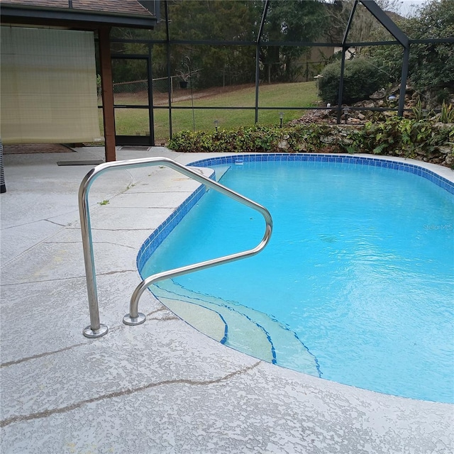 outdoor pool featuring glass enclosure and a patio