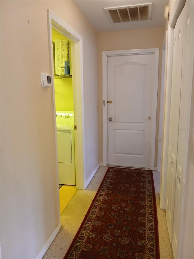 hallway with washer / clothes dryer, visible vents, and baseboards