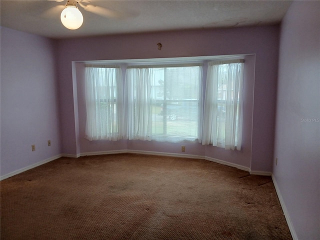 carpeted empty room featuring baseboards