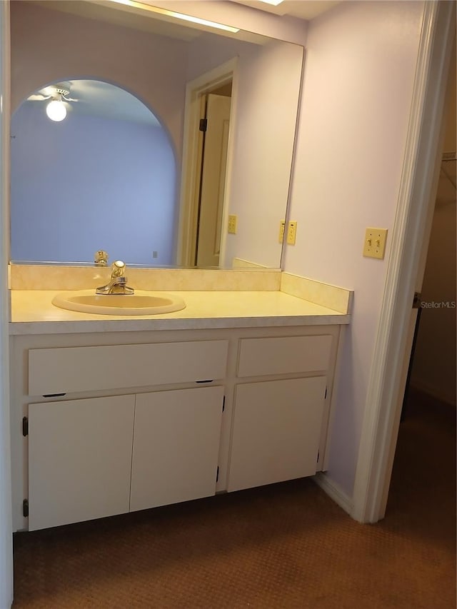 bathroom featuring a walk in closet, a ceiling fan, and vanity