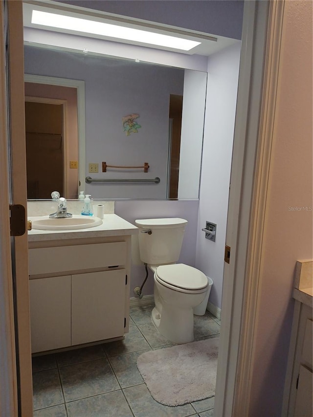 half bathroom with toilet, tile patterned flooring, and vanity