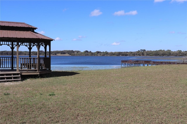 view of dock with a yard, a gazebo, and a water view