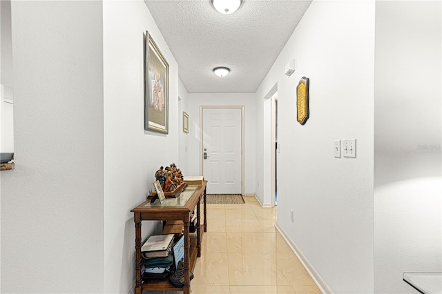 hallway with a textured ceiling and light tile patterned flooring