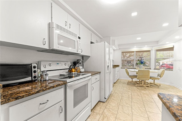 kitchen featuring dark stone countertops, white appliances, and white cabinets