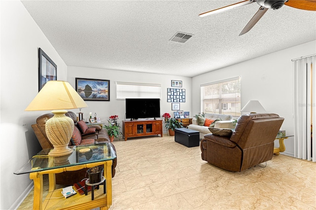 living room featuring ceiling fan and a textured ceiling