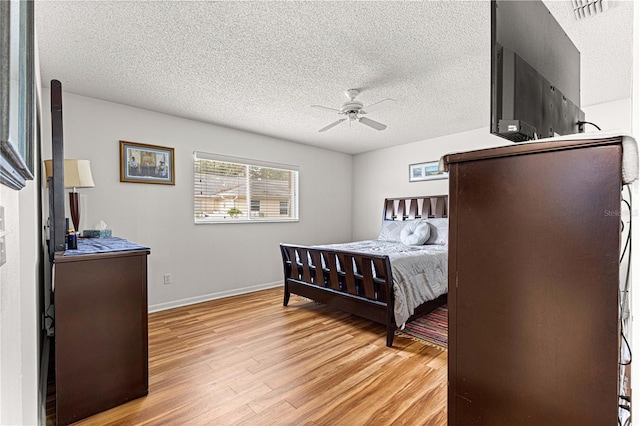 bedroom featuring ceiling fan, light hardwood / wood-style floors, and a textured ceiling