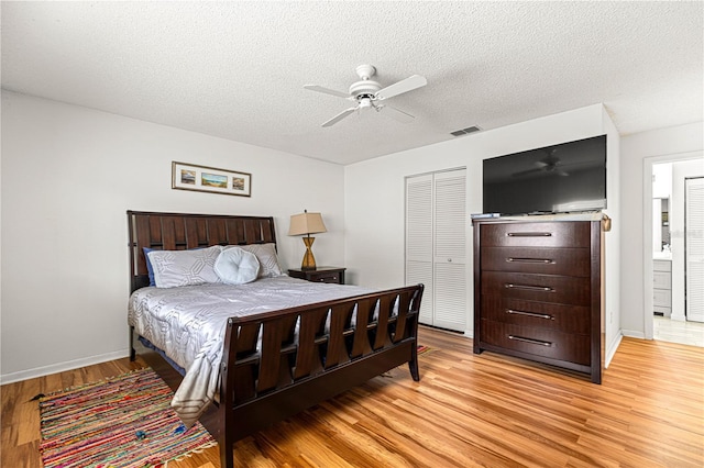 bedroom with ensuite bathroom, a closet, ceiling fan, a textured ceiling, and light hardwood / wood-style flooring