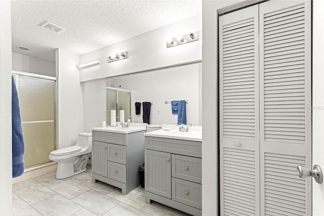 bathroom featuring vanity, a textured ceiling, a shower with shower door, and toilet