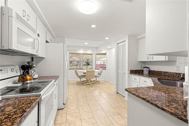 kitchen featuring white appliances, dark stone countertops, sink, and white cabinets