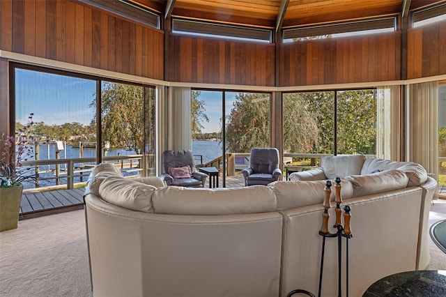 living room with a water view, light carpet, wood ceiling, and wood walls