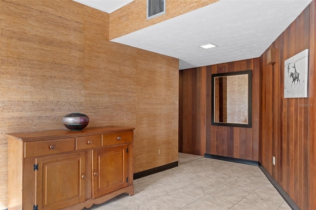 hall featuring light tile patterned floors and wood walls