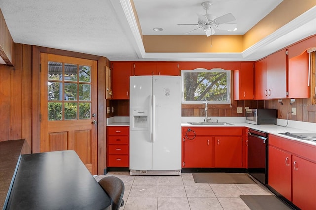 kitchen featuring light tile patterned flooring, sink, a tray ceiling, wooden walls, and black appliances