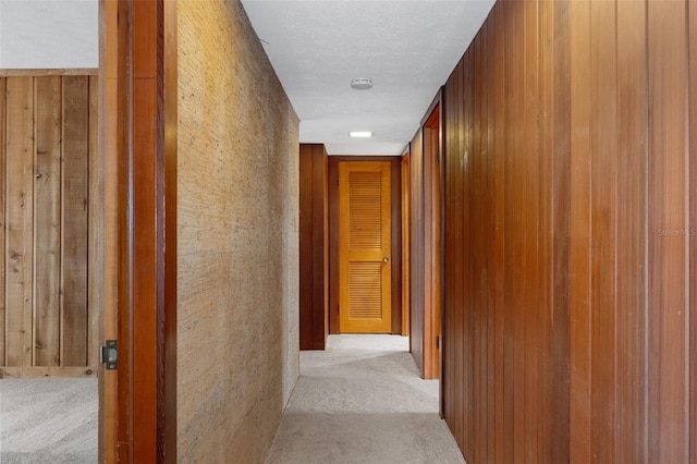 hall featuring wooden walls and light colored carpet