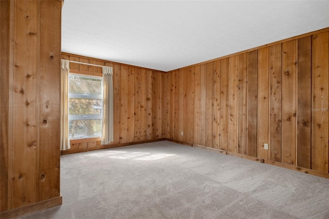 carpeted spare room featuring wooden walls