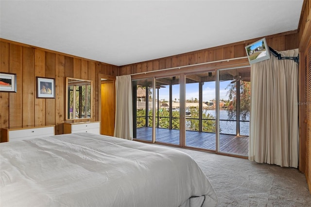 carpeted bedroom featuring a water view, access to outside, and wooden walls