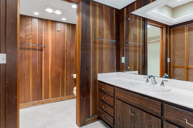 bathroom with vanity, toilet, and wood walls