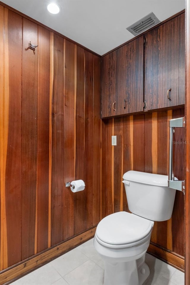 bathroom with tile patterned flooring, toilet, and wood walls