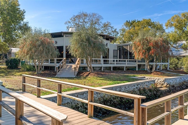 back of house with a water view and a lawn