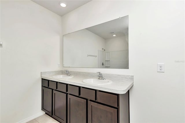 bathroom with tile patterned flooring, vanity, and walk in shower