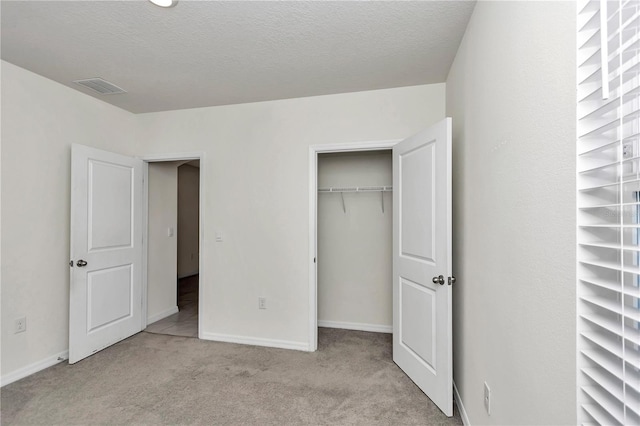 unfurnished bedroom with light colored carpet, a textured ceiling, and a closet