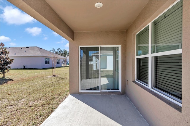 property entrance featuring a patio area and a lawn