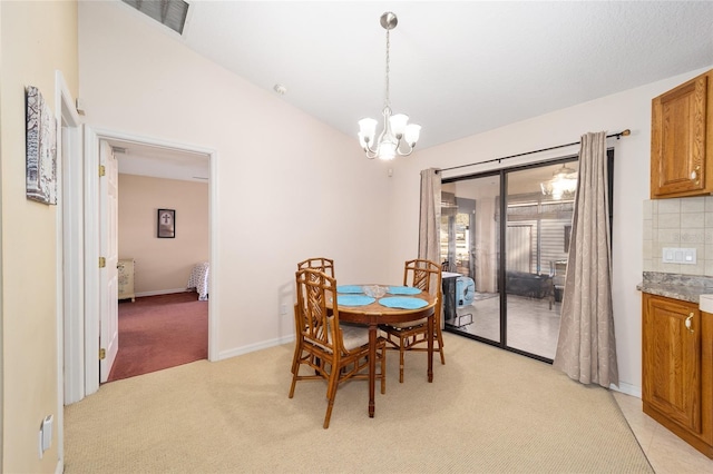 dining room featuring a chandelier, vaulted ceiling, and light carpet