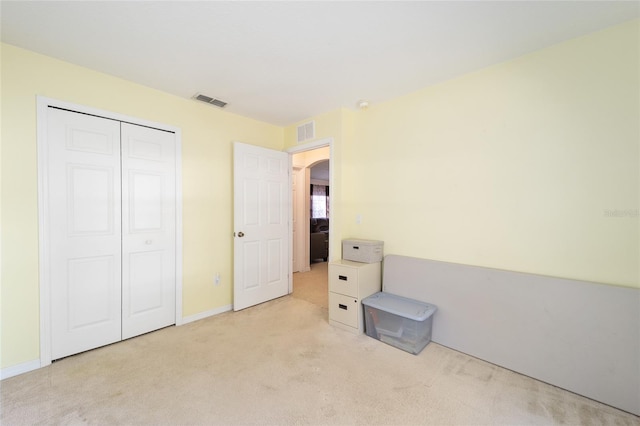 unfurnished bedroom featuring light carpet and a closet