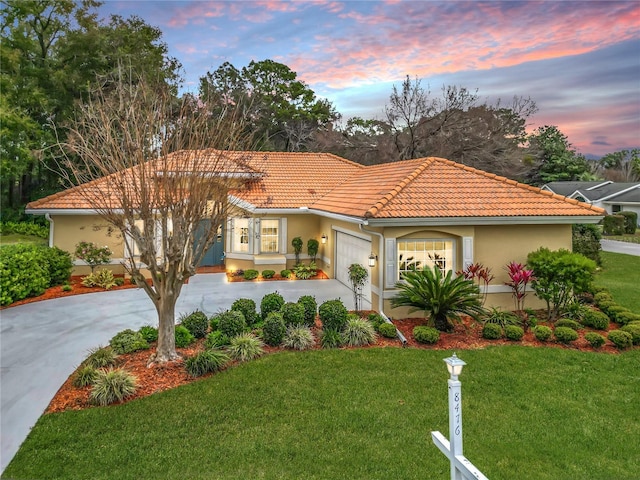 mediterranean / spanish home with a garage and a lawn