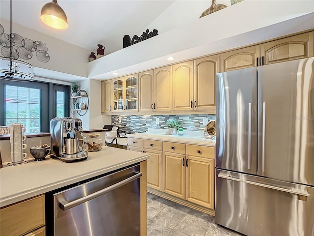 kitchen featuring stainless steel appliances, light brown cabinetry, and decorative light fixtures