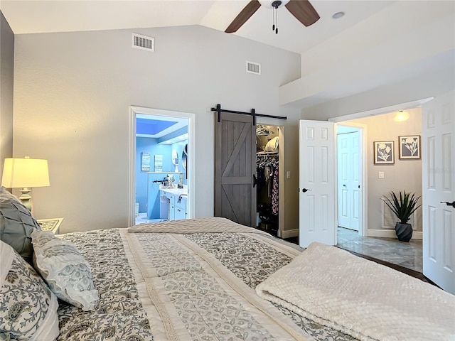 bedroom with ensuite bath, a walk in closet, high vaulted ceiling, ceiling fan, and a barn door