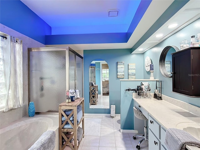 bathroom with tile patterned floors, a tray ceiling, separate shower and tub, and vanity