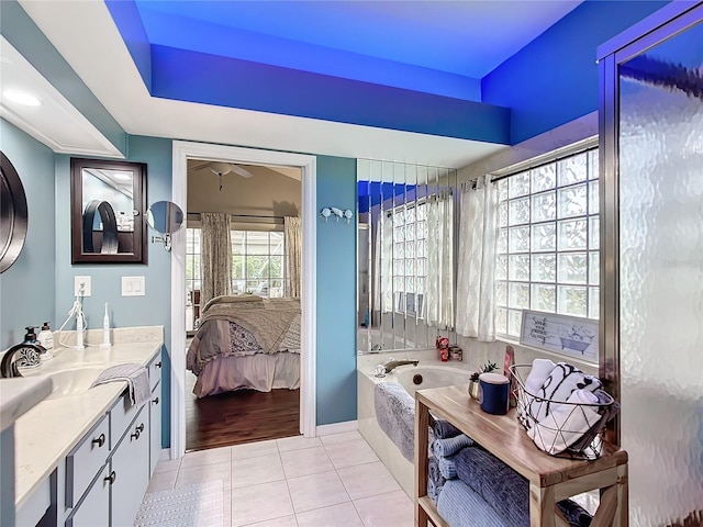 bathroom with tile patterned flooring, vanity, and tiled bath