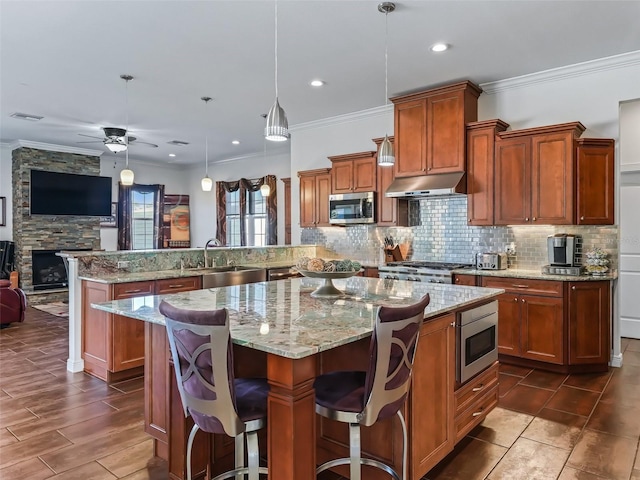 kitchen with stainless steel microwave, decorative light fixtures, sink, a kitchen breakfast bar, and kitchen peninsula