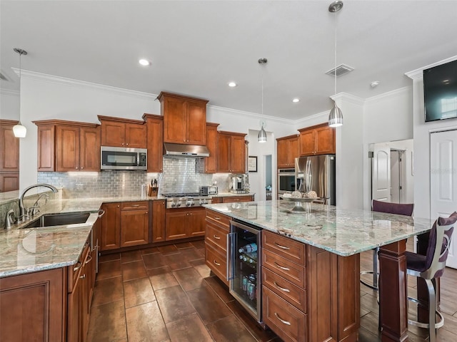 kitchen featuring sink, hanging light fixtures, stainless steel appliances, a center island, and beverage cooler