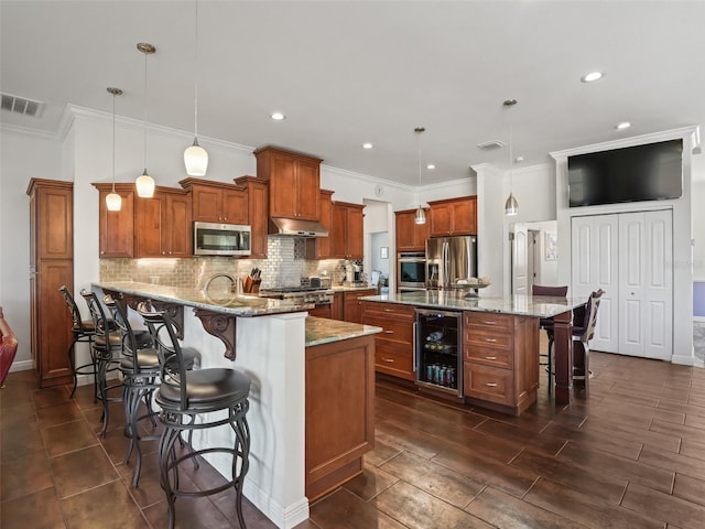 kitchen featuring pendant lighting, wine cooler, stainless steel appliances, and a kitchen bar