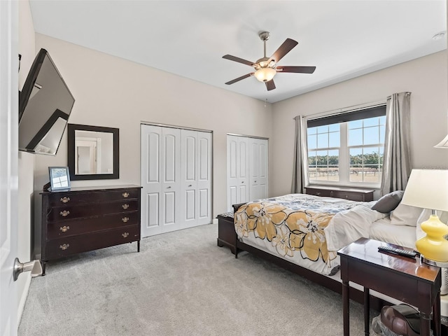 carpeted bedroom featuring multiple closets and ceiling fan