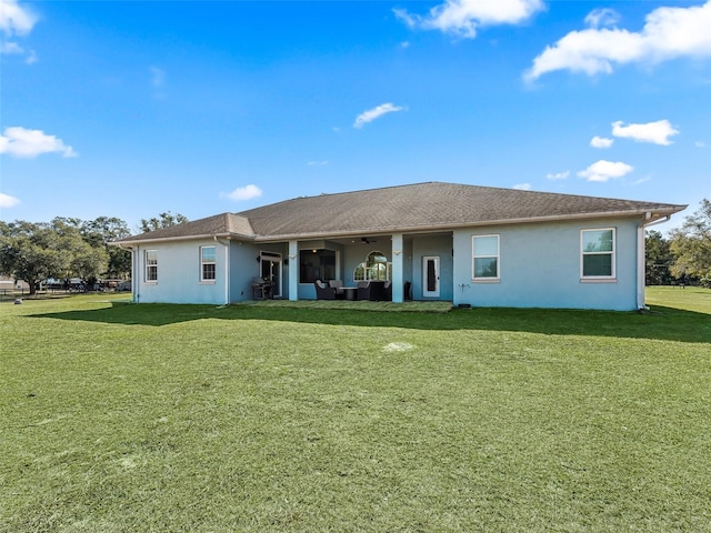 rear view of property featuring a lawn, an outdoor living space, and stucco siding