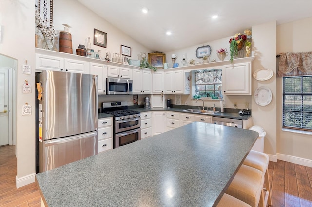 kitchen featuring sink, white cabinets, a kitchen bar, a center island, and stainless steel appliances