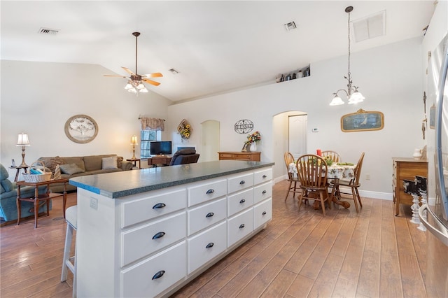 kitchen with lofted ceiling, dark wood-type flooring, white cabinetry, a kitchen breakfast bar, and a kitchen island